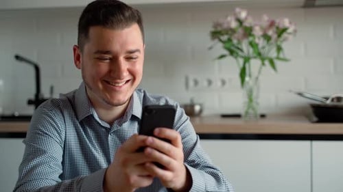 Young Adult Smiling at Phone in Kitchen