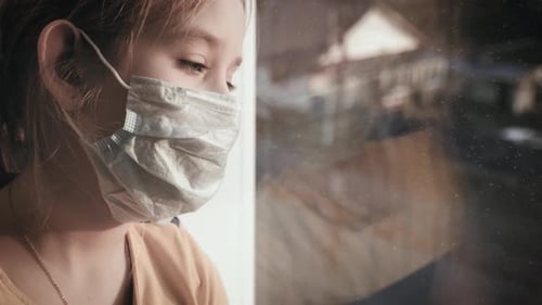 Little Girl in a Protective Mask Sits in Quarantine at Home