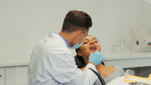 Young Dentist Checking Woman's Teeth at Clinic