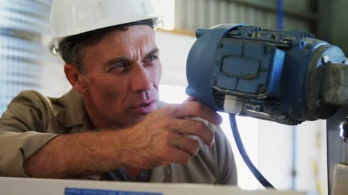 Man Inspecting Machinery with Tablet in a Factory
