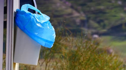 Papelera con bolsa de plástico en la puerta de la caravana