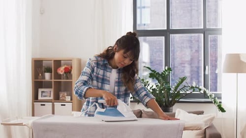 Young Woman Ironing Clothes at Home