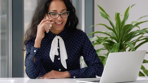 Happy female make mobile call. Smiling young mixed race business woman talking on phone.