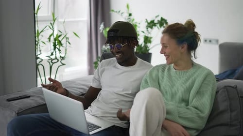 Happy Couple Using Laptop on Couch at Home