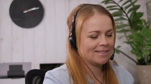 Femme souriante travaillant comme opérateur de soutien à la clientèle avec casque dans un centre d'appels