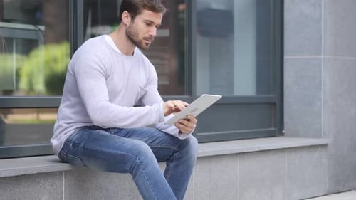 Handsome Man Using Tablet While Sitting Outside Office Browsing Online