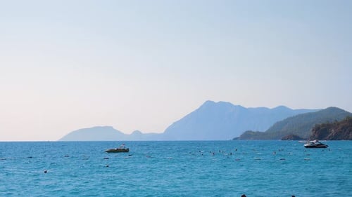 Les bateaux roulent sur les vagues près de la mer, les gens se baignent dans la mer