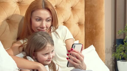 Mother and Child Using Phone on Bed