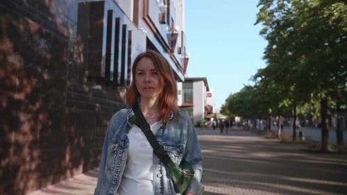 Young Girl Walks Down the Street and Checks Her Smartphone