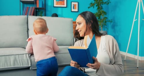 Woman Reads Book To Baby Near Couch