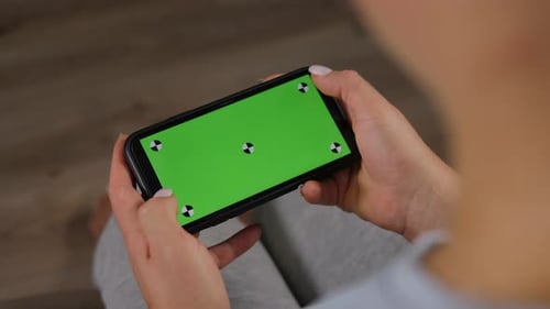 Closeup of a Young Woman Holding a Smartphone with a Green Screen