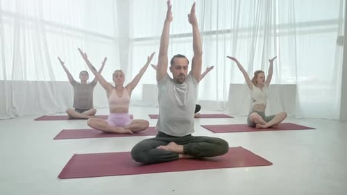 Yoga Class Practices Poses in Bright Studio