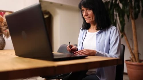 Woman Using Stylus and Graphics Tablet at Home