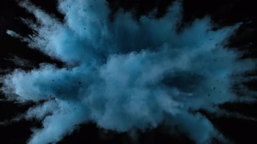 Colorful powder/particles fly after being exploded against black background. Slow Motion.