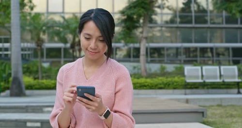 Young Woman Uses Smartphone in Urban Park Setting