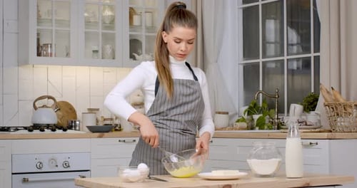 Woman Whisking Eggs in a Bright Kitchen