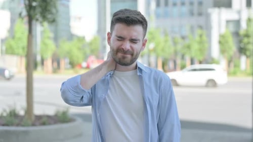 Young Adult Rubbing His Aching Neck in City