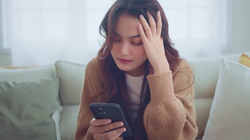 Woman Using Phone, Looking Stressed at Home