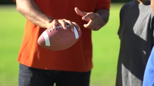 Adult Holding Football with Children Outside