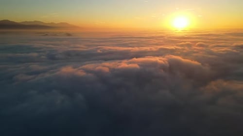 Luftaufnahme des Fliegens über eine Wolkenschicht bei Sonnenaufgang