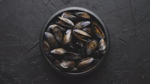 Fresh and Raw Sea Mussels in Black Ceramic Bowl Placed on Dark Stone Background