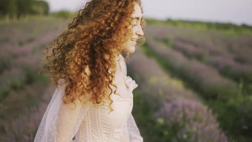 Schönes schlankes Mädchen im rosa Kleid wirbelt im Sommer bei Sonnenuntergang auf einem Lavendelfeld