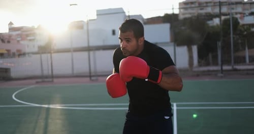 Man Shadow Boxing on City Court at Sunrise