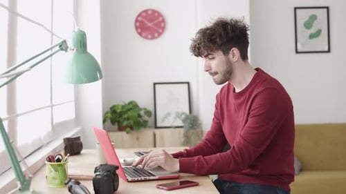 Young Hipster Adult Man Working on Laptop Computer From Home Office