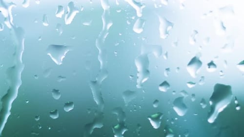 Raindrops Streaming Down Glass Surface in Close-Up