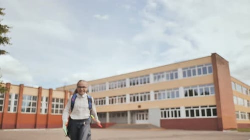 Glückliches elfjähriges Schulmädchen läuft nach der Schule mit einem Rucksack