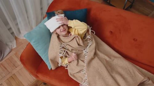 Sick Child Lies on Couch with Cold Compress