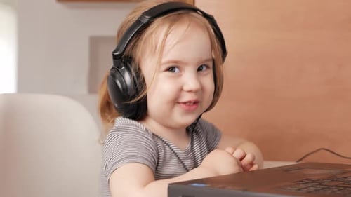 Cute Child with Headphones Using Laptop Computer