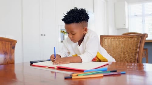 Front view of attentive black boy doing his homework at comfortable home 4k