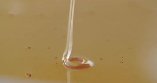 High angle shot of honey flowing into more honey. Honey dripping clockwise and counterclockwise. Mes
