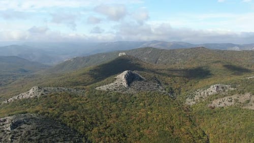 Aerial View of Rocky Mountains Covered with Autumn Forest Under Blue Sky with White Clouds