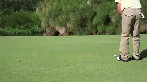 Golfer Prepares to Putt Golf Ball on Green