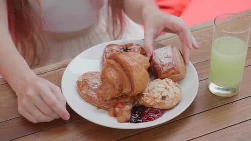 Closeup of Girl Eating Fresh Bun Sitting in Outdoor Cafe Breakfast in Hotel