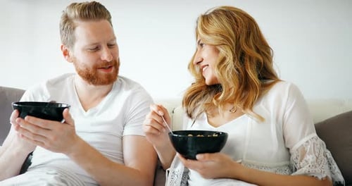 Happy Married Couple Being Romantic in Bed Sharing Cereal