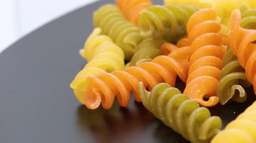 Close up view of fusilli, italian colored macaroni, macro shot in 4k. Rotating motion, view from abo