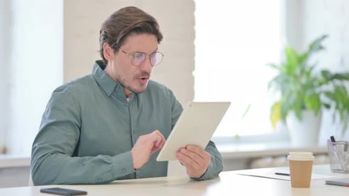 Adult Man Using Tablet at Desk in Office