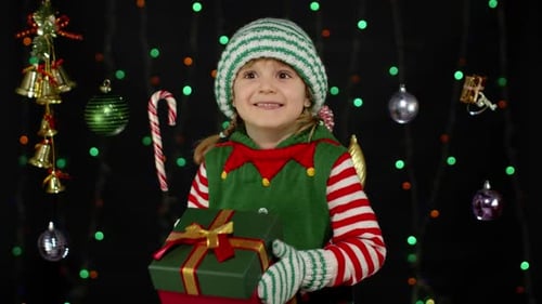 Smiling Girl in Elf Costume Holding Christmas Gift