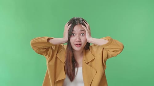 The Shocked Asian Woman Grabbing Her Head While Saying Wow On Green Screen Background In The Studio
