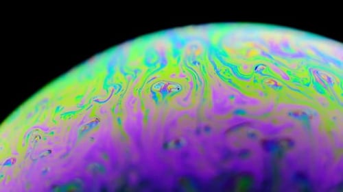 Regenbogen-Seifenblase auf dunklem Hintergrund. Nahaufnahme einer bunten Oberfläche