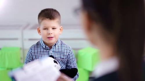 Mittelgroßer kleiner süßer Junge, der bei einer Therapiesitzung mit einer Kinderpsychologin über ein Problem spricht