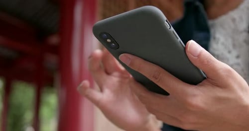 Close up of woman use of mobile phone in Chinese garden