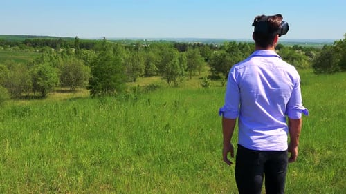 Young Handsome Man Uses Virtual Reality Glasses - Countryside in the Background