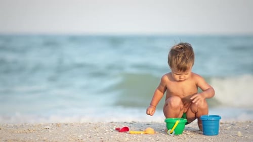 Kid Collects Shells and Pebbles in the Sea on a Sandy Bottom Under the Summer Sun on a Vacation