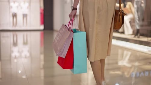 Happy Woman Leaving Store in Shopping Mall with Many Paper Bags Full of Purchases