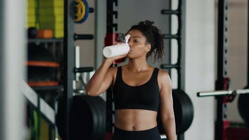 Woman Drinking Water During Workout in Gym