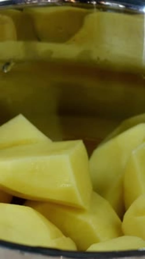 O chef coloca pedaços grandes de batatas cruas na panela e despeja com água fria e limpa para cozinhar